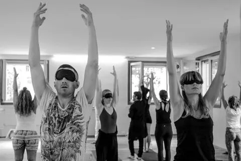 A group of people practicing yoga while wearing blindfolds