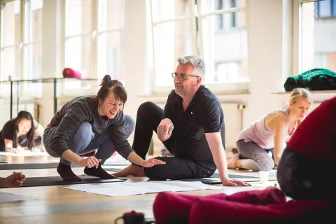 A man and woman smiling and collaborating over papers on a studio floor