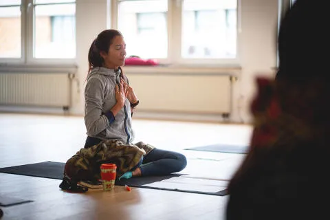 A woman sitting on a yoga mat with her eyes closed